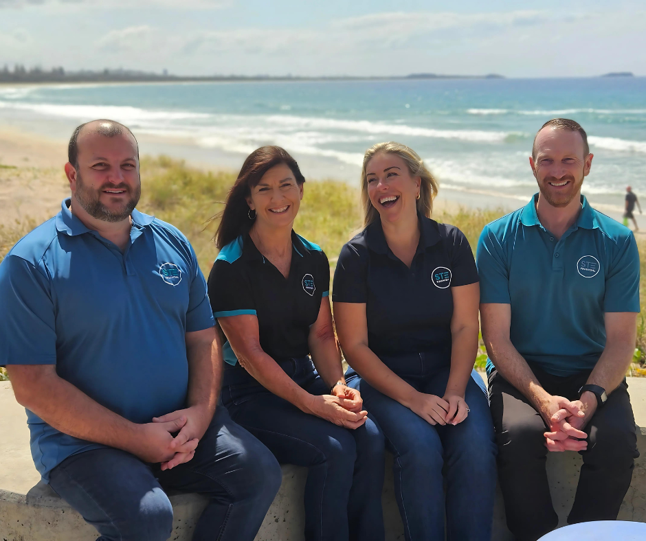 The STE Financial team sitting on the sea wall at Kingscliff beach